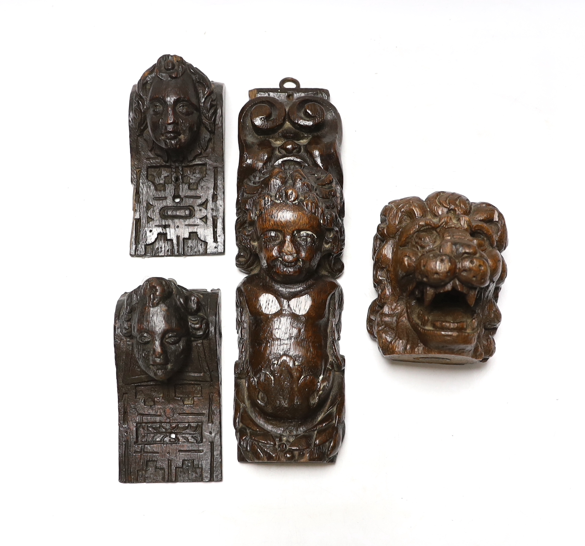 Three 17th century carved oak figural corbels together with corbel end in the form of a lion, largest 30cm high